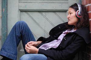 Gesangslehrerin Anne sitzt auf der Treppe hört Musik